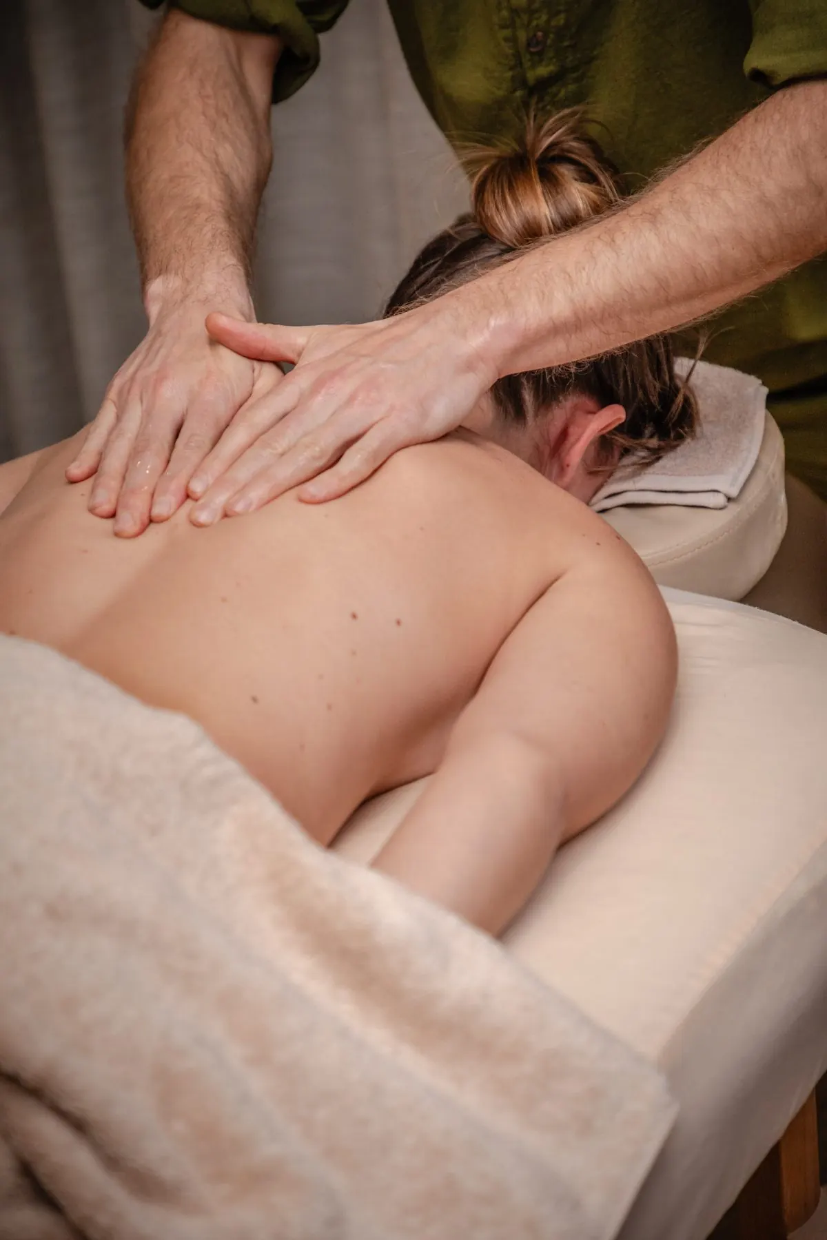 Therapist working with flat hands across a client’s back