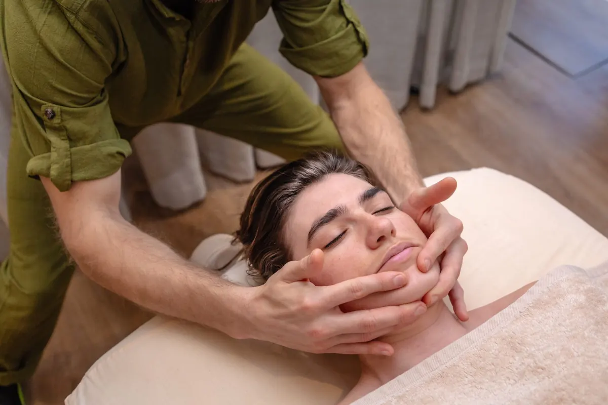 Therapist massaging a client’s face and temples